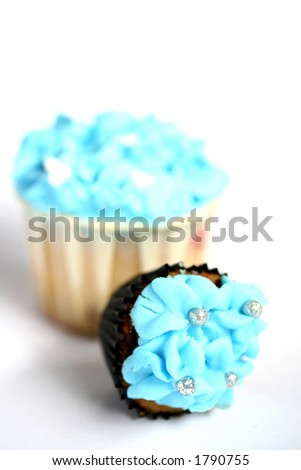 Two mini cupcakes with blue frosting, isolated on white with copy space