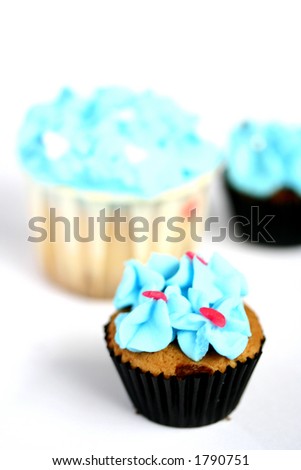 Three mini cupcakes with blue frosting isolated on white with copy space