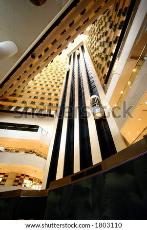 A grand lobby of a high rise building with two moving internal elevator