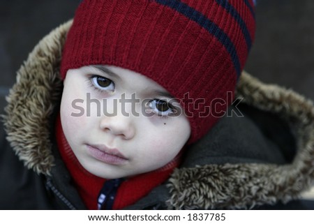 A boy feeling cold as he went out for a walk in winter, completes with hat, scarf and a winter coat