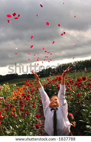 A young girl throws a bunch of dahlia petals in the air, in a flower farm