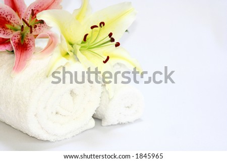 Two white towels with two lilies on white, suitable for spa or therapy setting.