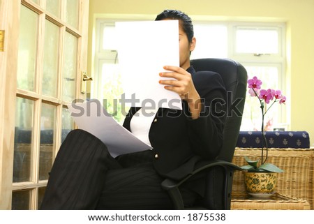 A businesswoman studying her notes, in her casual office surrounding