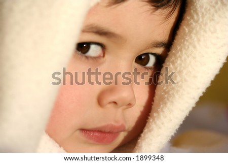 A young toddler boy plays imaginary games with his blanket, beautifully lit by the evening glow of the sun.