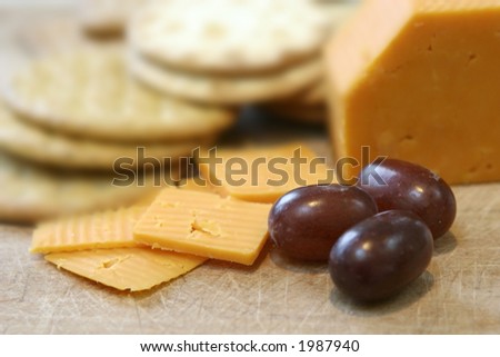 Close up of leicester red cheese and biscuits on wooden board and seedless red grapes.