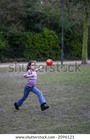A young active girl having a game of football in the park.