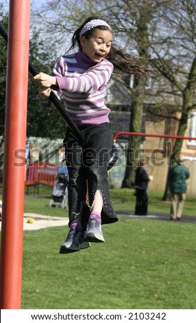 A young girl being thrown in the air from the force of the playground swing.