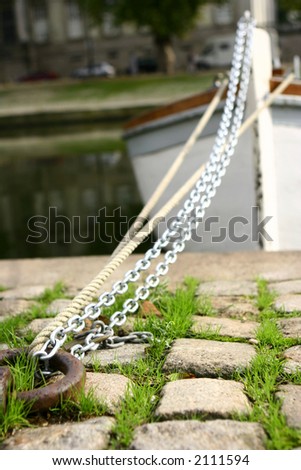 A boat moored in a lake by chains and ropes.