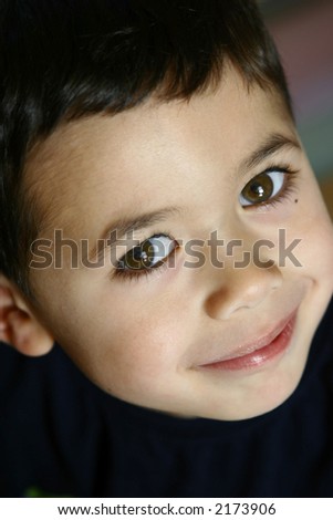 A happy little boy with brown eyes smiling into the camera.