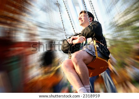 A man reliving his childhood, having a go at the fairground ride with movement blur.