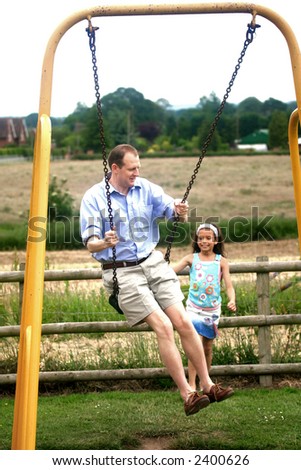 A man on a high swing showing his daughter how high he could go. Concept : Facing fear.