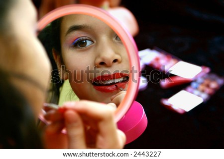 A little girl playing with makeup, pretending that she\'s grown up, concept of imagination and ambition.