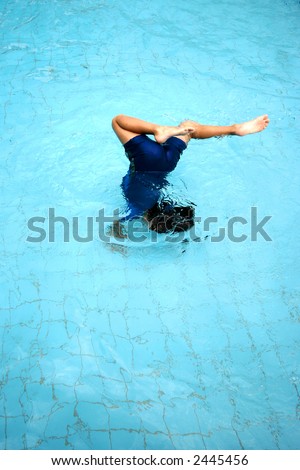 A young boy doing a somersault in the swimming pool, concept of fear, courage and confidence.