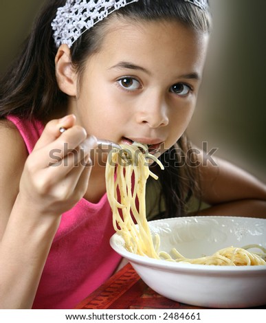 Young girl enjoying a bowl of pasta with tomato sauce. Concept of healthy eating.