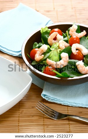 Bowls of fresh prawn salad with cherry tomatoes, baby spinach leaves and fresh salad leaves.
