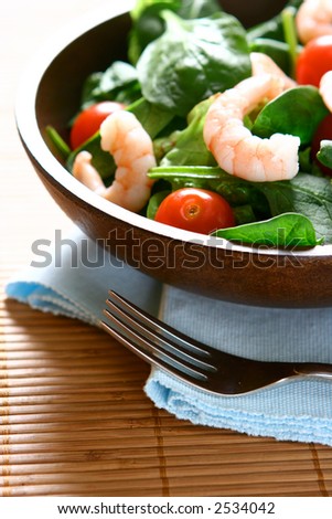 Bowls of fresh prawn salad with cherry tomatoes, baby spinach leaves and fresh salad leaves.