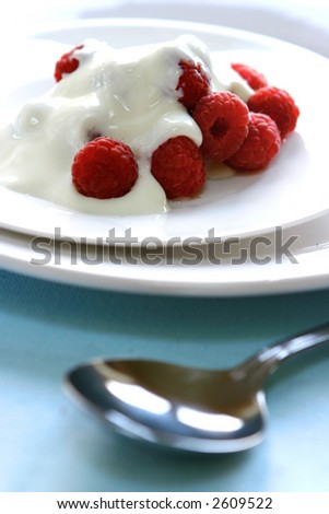 A plate of fresh raspberries served with yogurt on white plate. Concept of healthy desert.