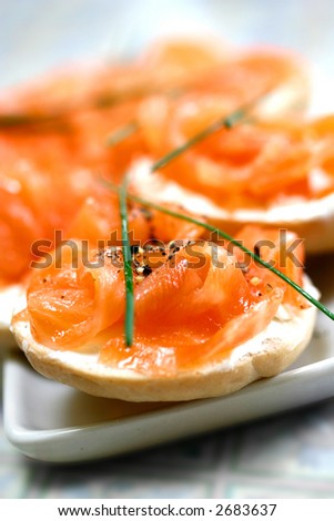 Smoke salmon on cream cheese on mini bagel with freshly crack black pepper and garnishing of chives.