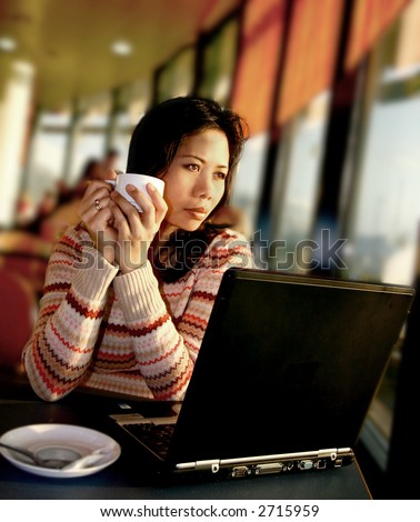 A woman staring out onto the airport runaway as she has coffee in the lounge, waiting for her flight departure.