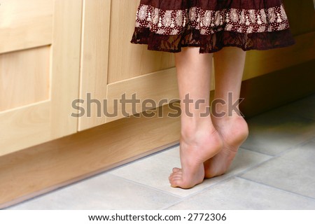 stock photo Conceptual image of a pair of young feet on tip toes trying