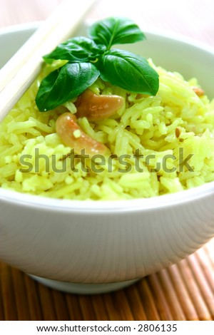 A bowl of lemon flavoured fragrant rice with tasty cashew and herbs, garnished with a sprig of basil.