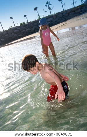 A little boy and his sister enjoying the warm water as they watch for little fish.