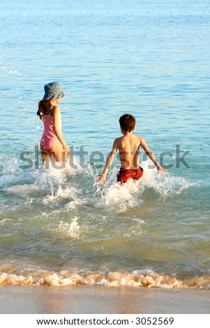 A brother and his sister making big splash as they both entered the warm water of the sea on a warm afternoon.