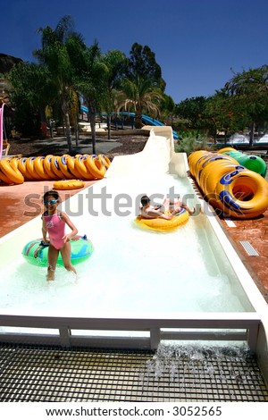 A young girl enjoying the float ride down the slide with her father at the waterpark.
