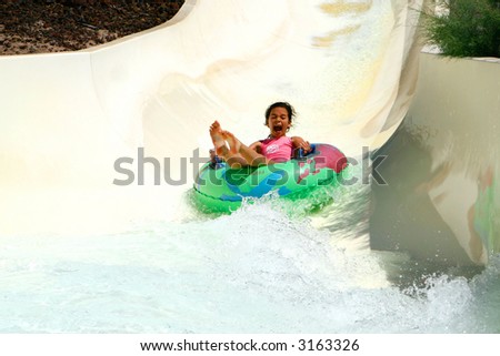 Young girl having lots of fun on rubber ring going down the water slide.