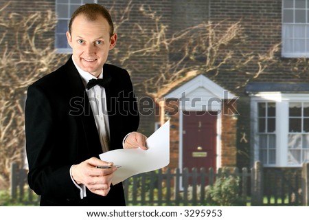 Cheerful male property agent handing a form and paper to viewer with beautiful property in the background.