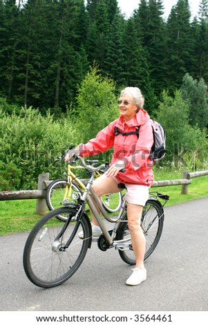 Mature woman enjoying the outdoor life in the pine forest, riding on her bicycle.