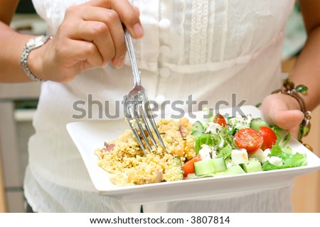 Woman having light meal of couscous with greek salad.