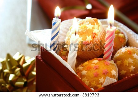 Boxed gift of sweet cupcakes with sprinkling of sugar stars and burning candles.