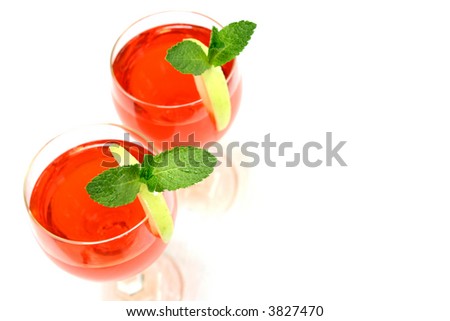 Two glasses of red cocktail with sprig of mint on a slice of green apple.