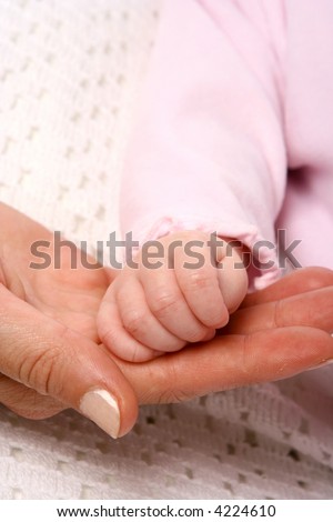 Newborn baby girl\'s tiny hand on her mom\'s palm.