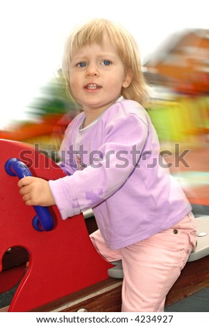 Toddler girl enjoying a ride on the wooden pony see saw in the playground.