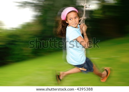 stock photo Young girl swinging fast on the rope swing tied to a tree