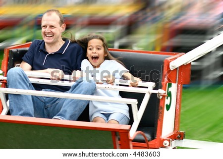 Father and daughter enjoying the fast octopus ride at the amusement fair in the park.