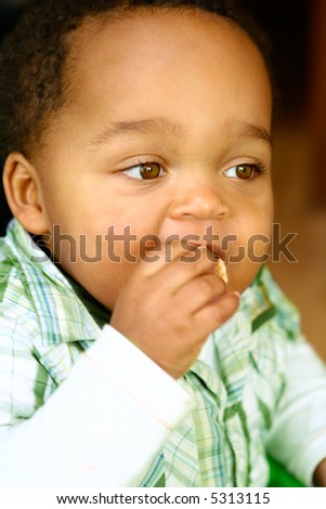Young toddler boy learning how to feed himself with a piece of toasted bread.