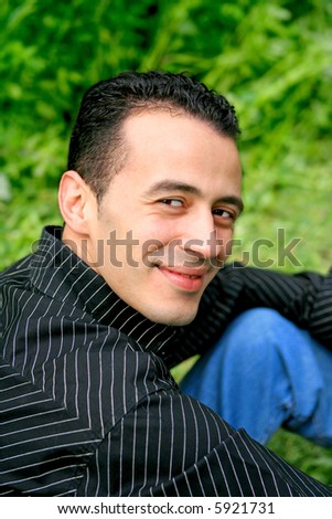 Young mediterranean man outdoors, looking sideways in casual clothing.