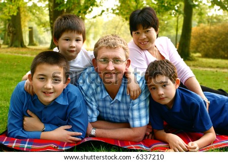 A mix-marriage family consisting of the parents and their three boys, enjoying the autumn park.