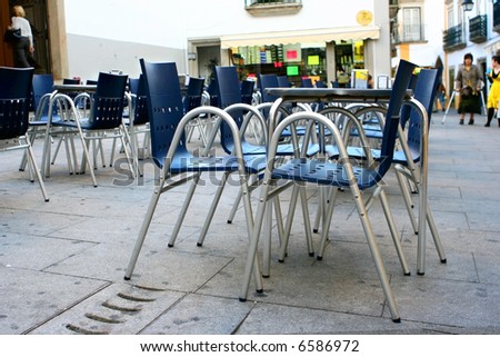 Outdoor dining area made up of contemporary style metal seats on stoned paving.