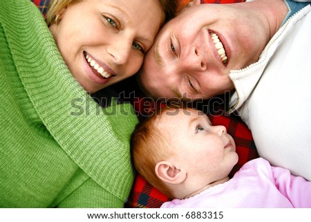 Young family lying on picnic rug , enjoying the outdoors.