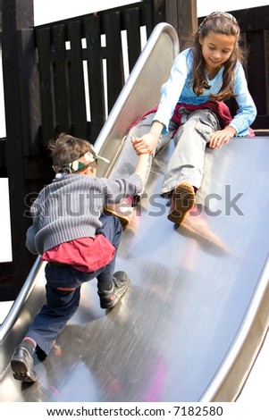 A sister pulling her brother up the slide