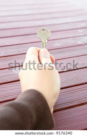 A hand handing out a single key.