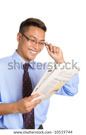 Young Asian businessman smiling happily as he reads about his investment interest in the newspaper