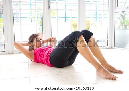 Young Asian woman doing sit ups to strengthen stomach muscle in calm home environment