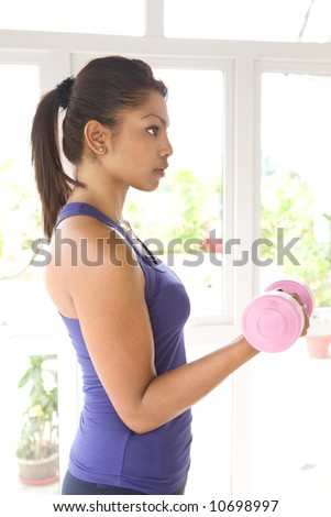 Young female in fitness outfit lifting dumbell in one hand, isolated
