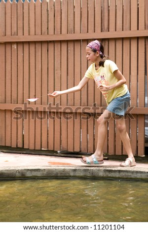 Young girl rushes as she successfully caught a fish in her net from the fish pond.