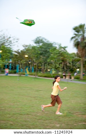 Young girl having fun pulling her kite as she runs in the field